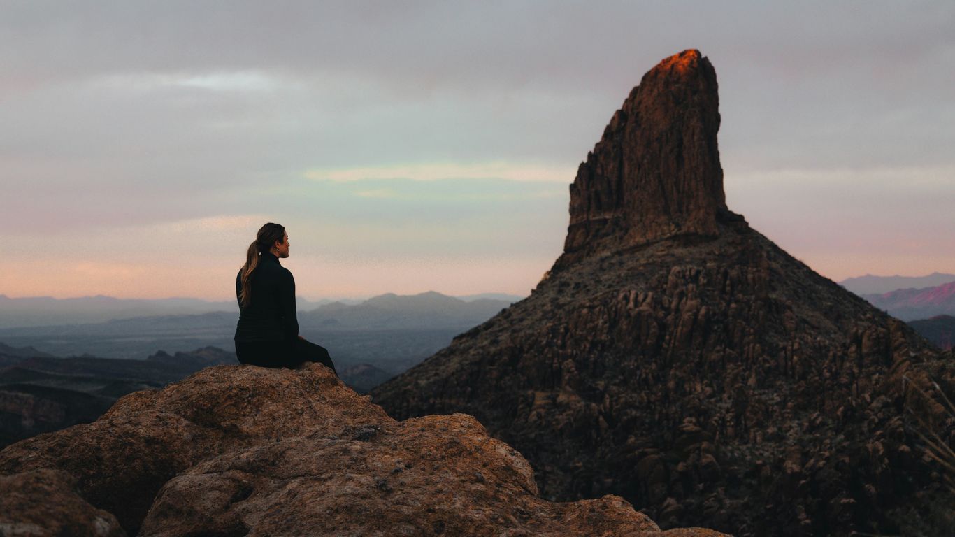 a woman sitting on top of a large rock