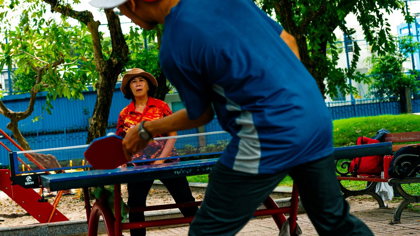 Two people playing table tennis outdoors