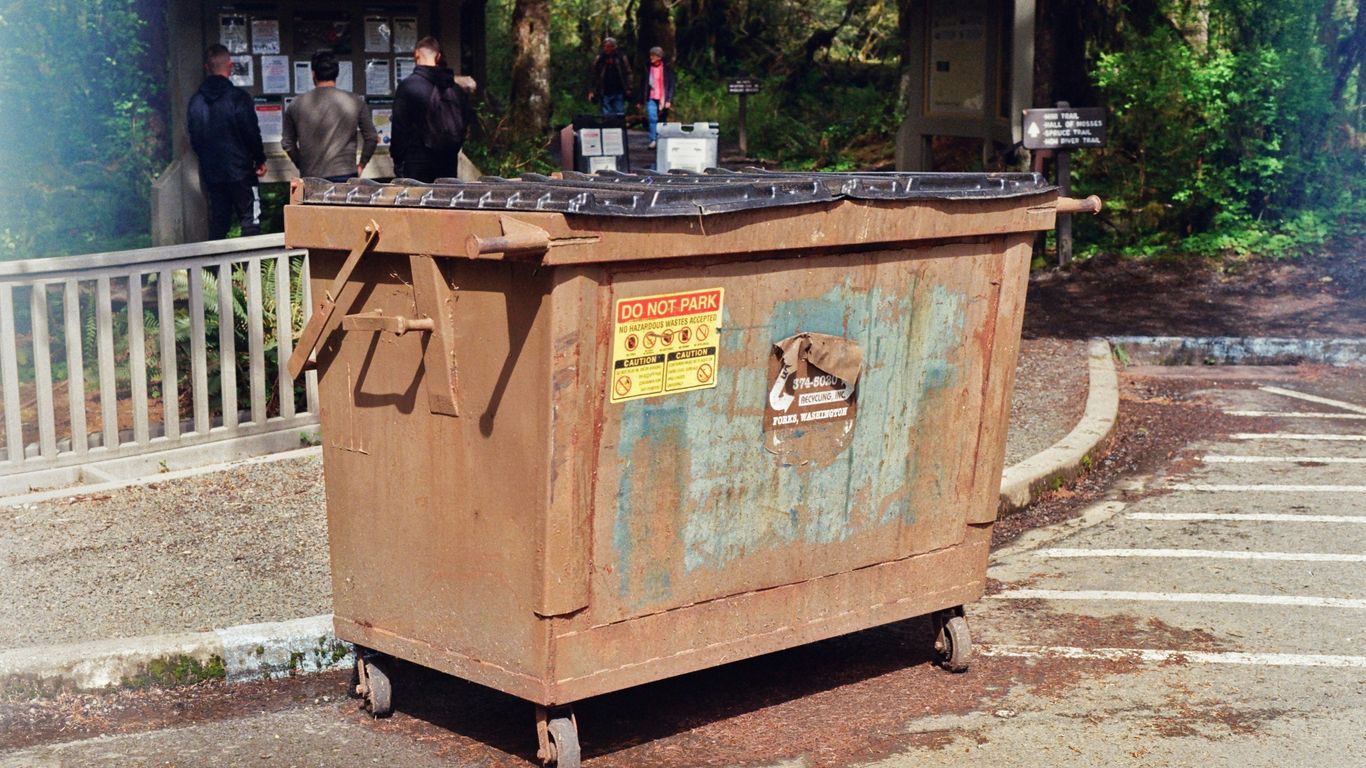 a trash can sitting in the middle of a parking lot