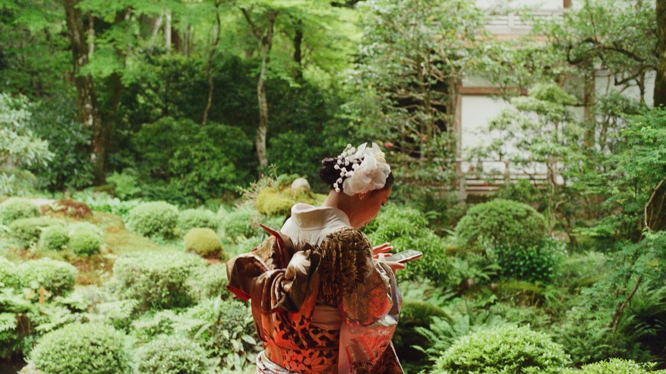 A woman in kimono enjoys a garden view.