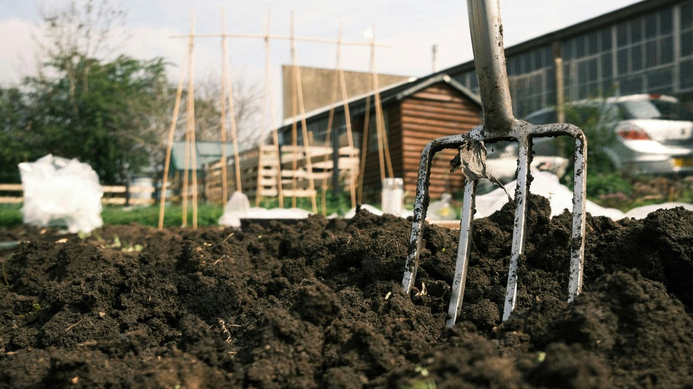 a garden fork stuck in a pile of dirt
