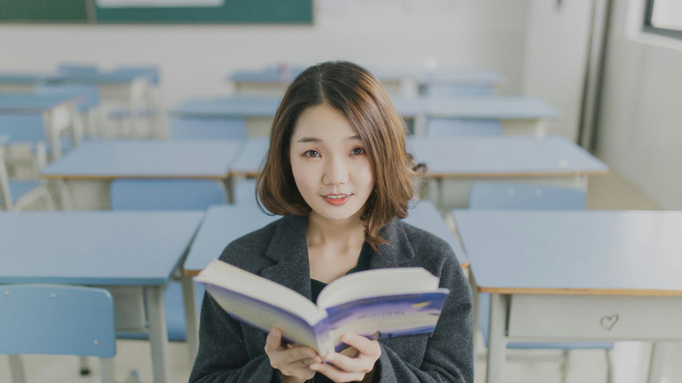 woman reading book sitting on chair in room