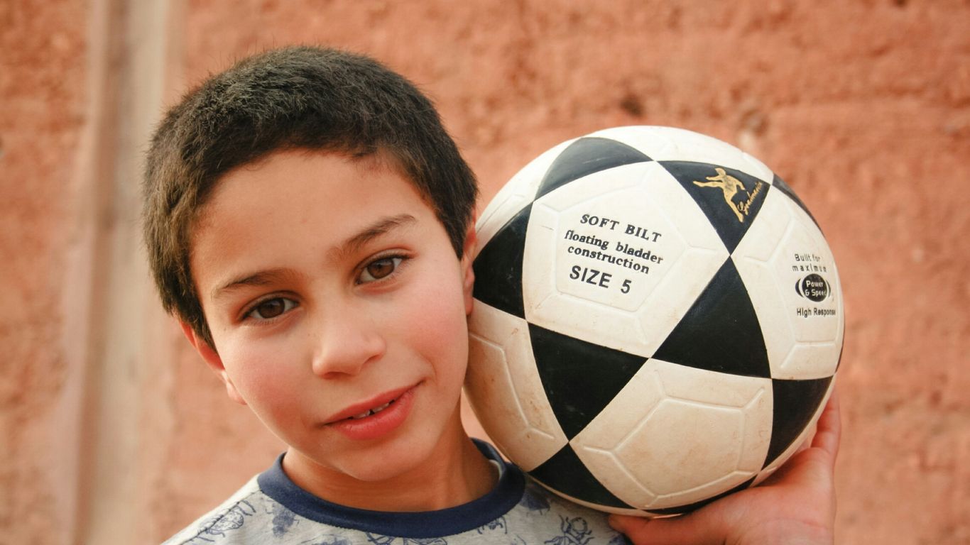 a boy holding a football ball