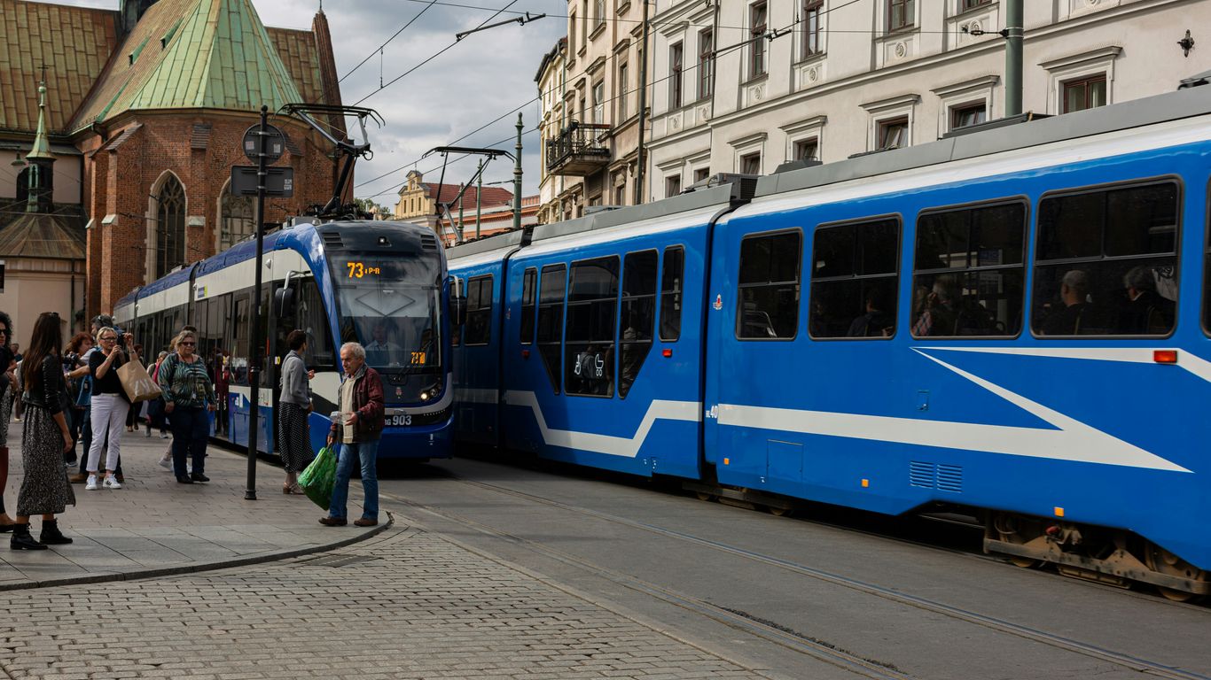 people walking near blue and white train under white and blue sky during daytime