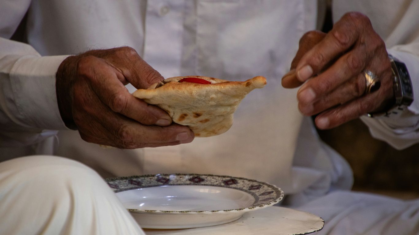 A man in a white shirt is holding a piece of food
