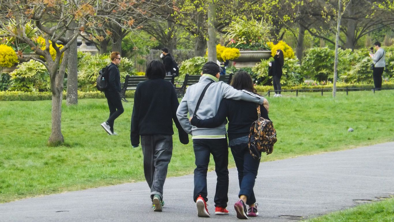 Three people are walking on a path in the park.