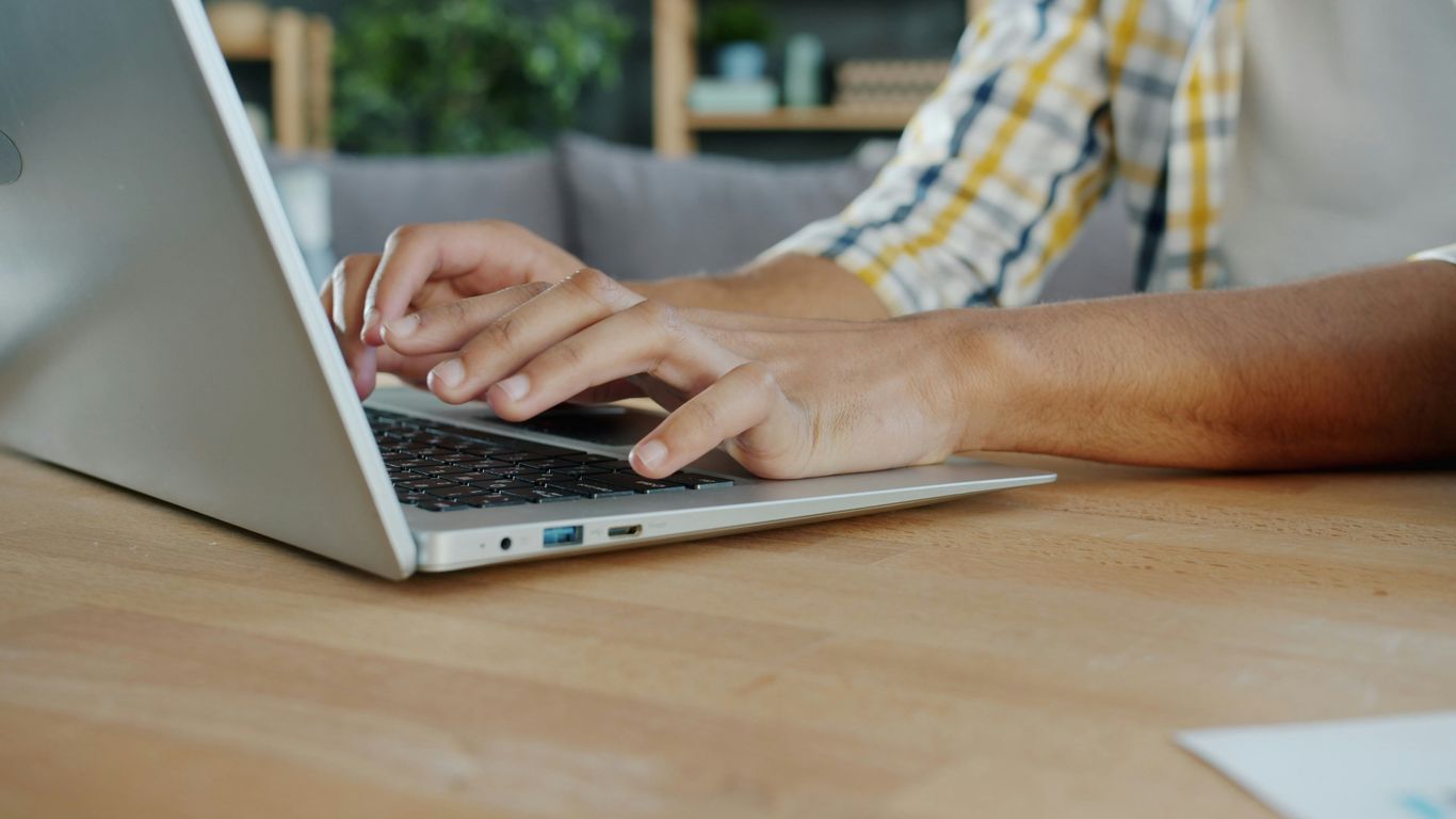 Hands typing on a laptop computer keyboard.