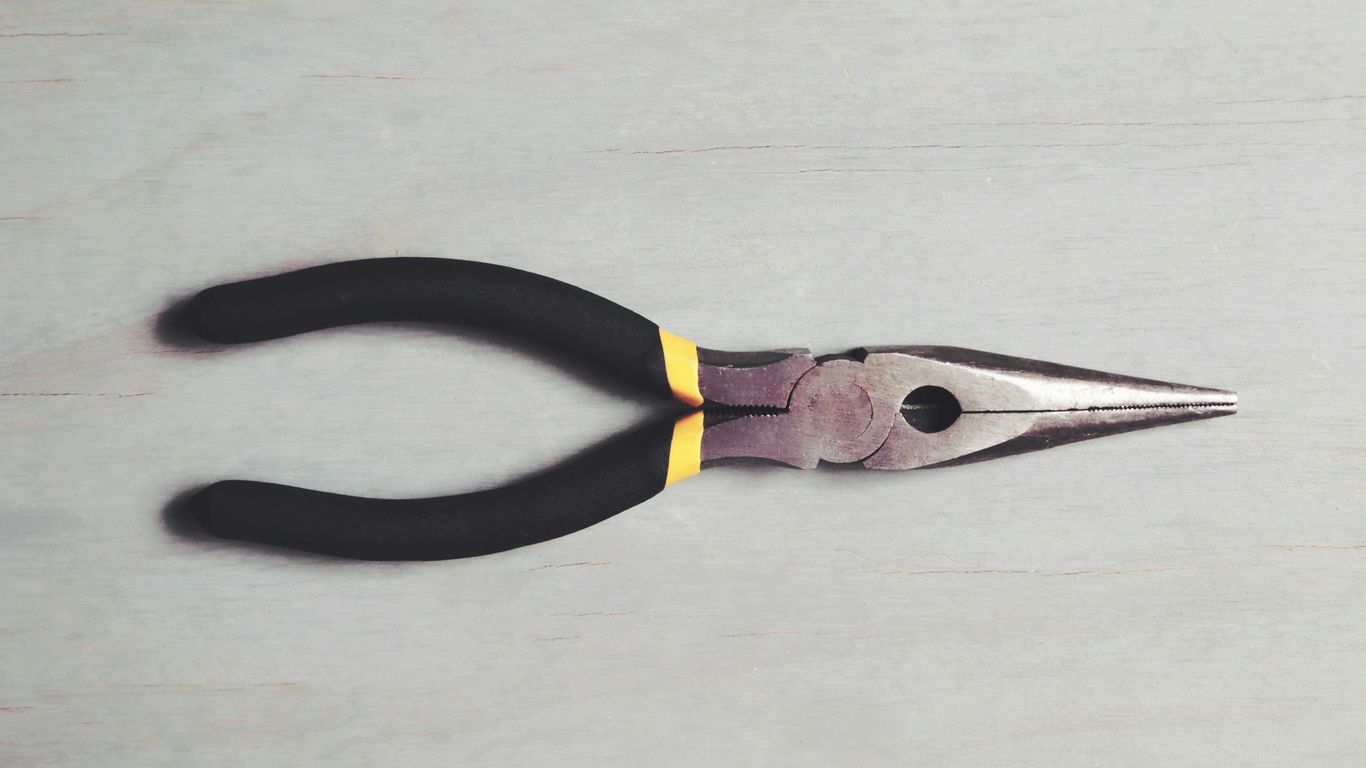 A pair of black and yellow pliers on a white surface