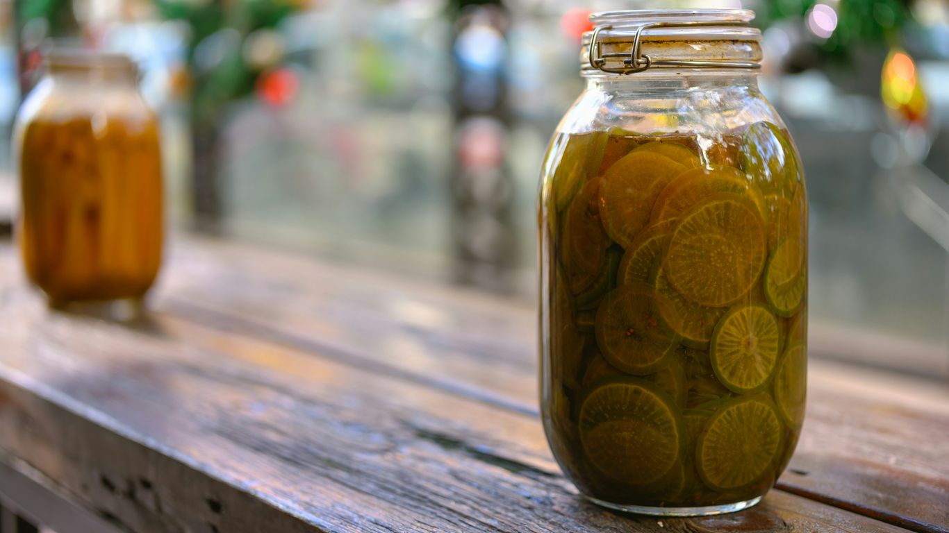 Two jars of pickles sitting on a wooden table