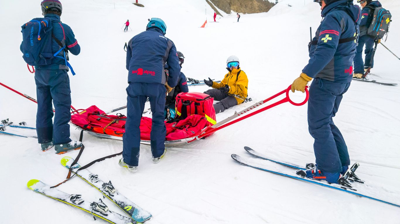 Ski patrol assisting an injured skier on a snowy slope.
