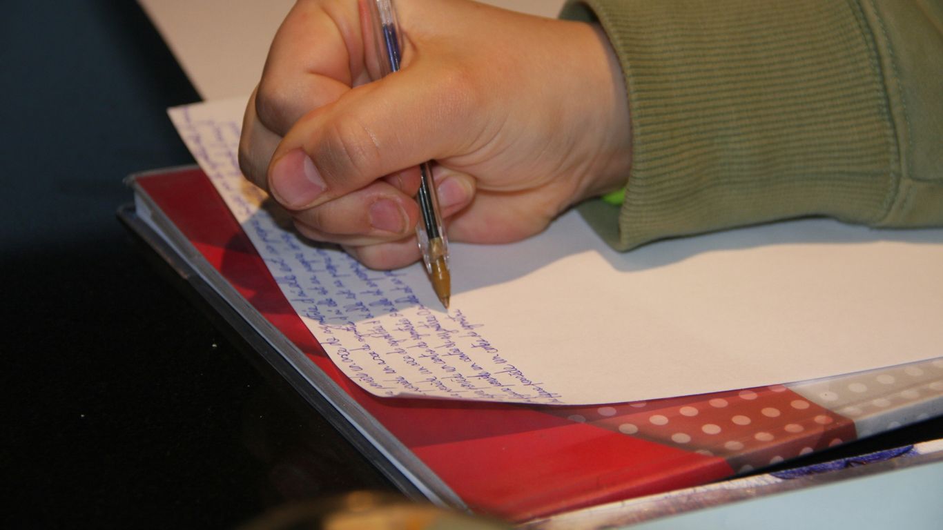 a person writing on a piece of paper with a pen
