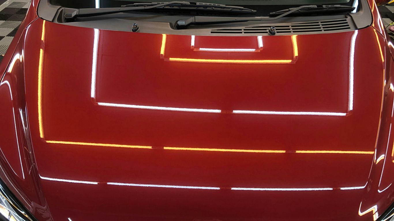 the hood of a red car with yellow lines on it