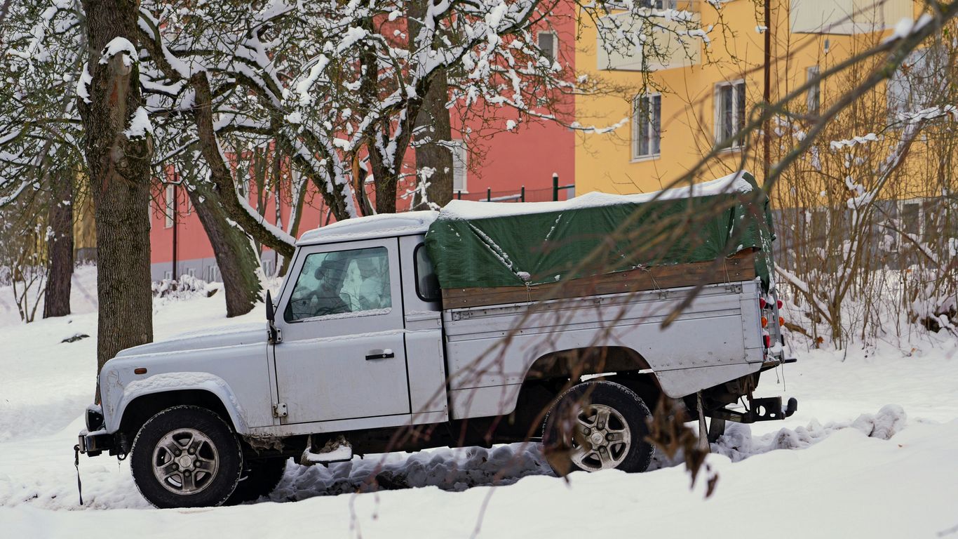 a white truck parked in the snow next to a tree