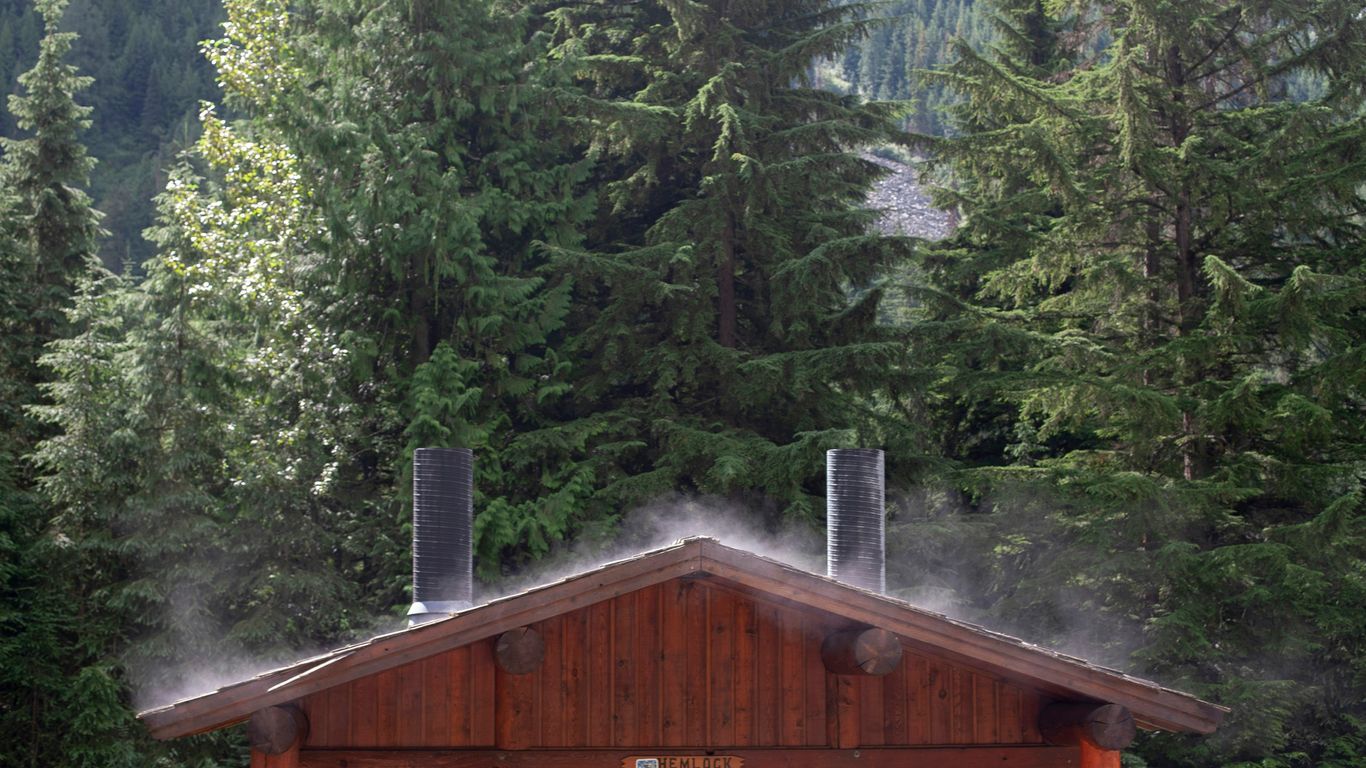 a cabin in the woods with smoke coming out of the chimneys