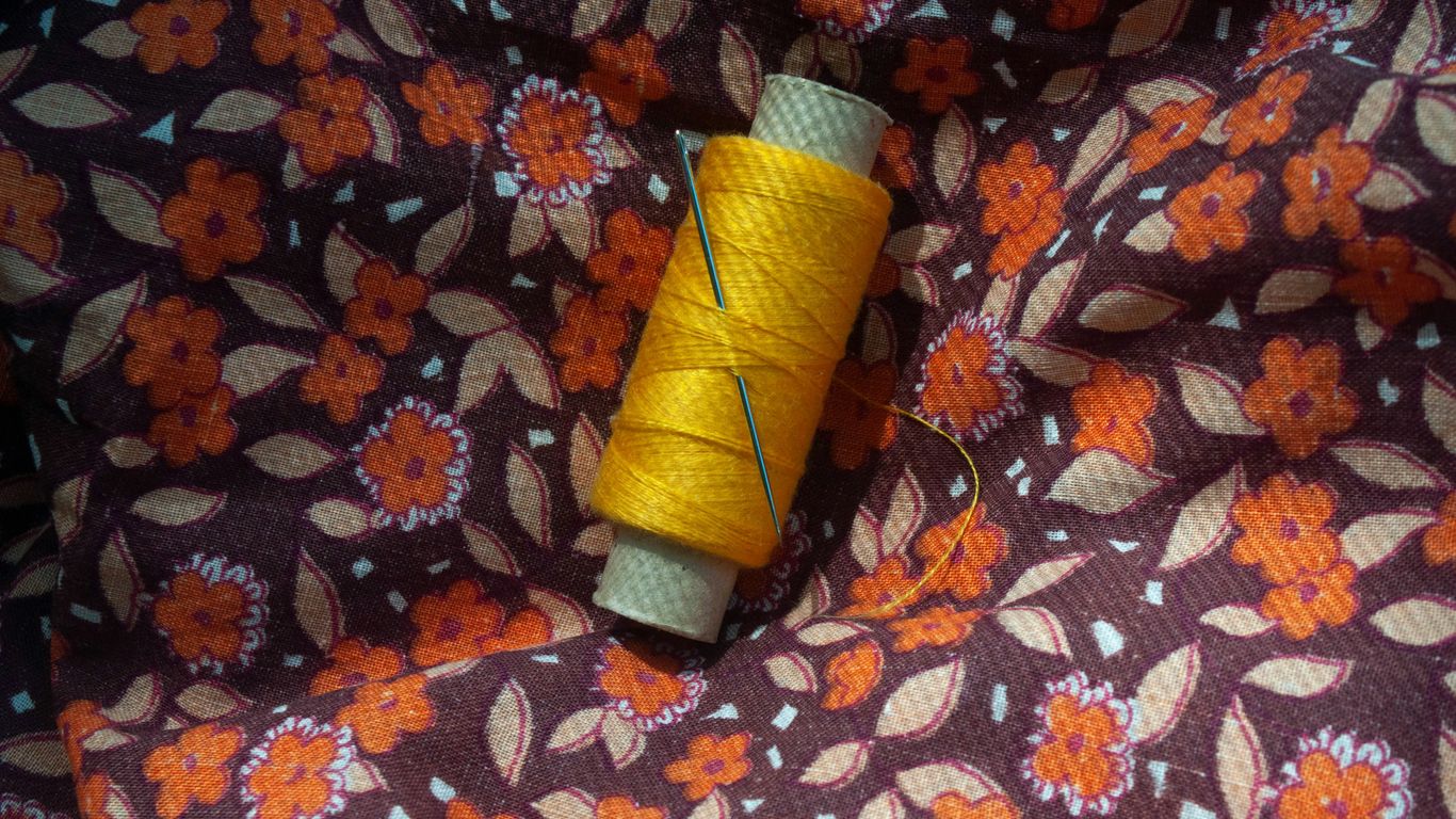 a spool of thread sitting on top of a flowery fabric