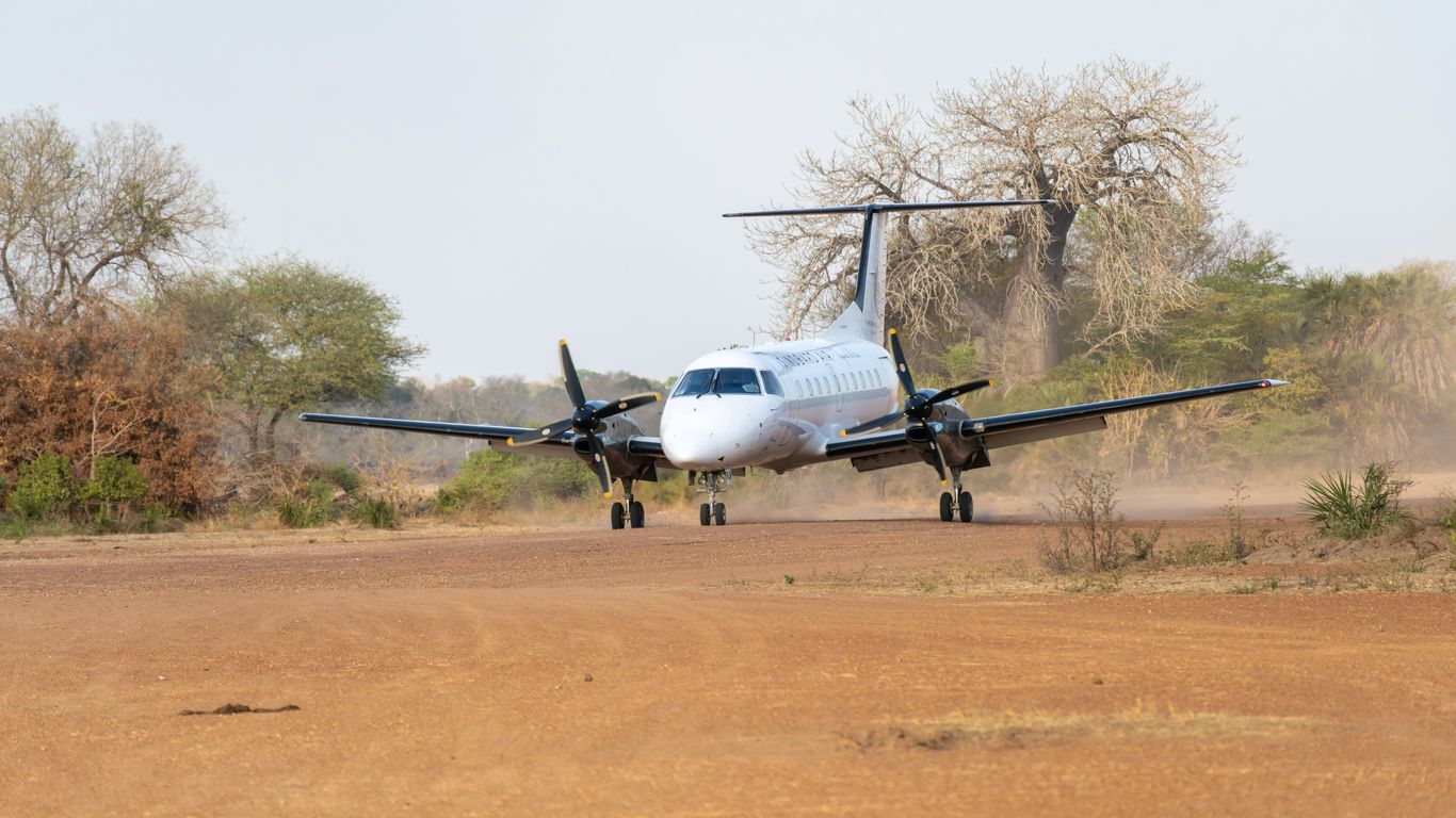 a small plane landing on a dirt runway