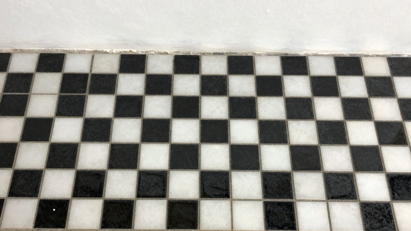 Mosaic black and white tiles in a checkerboard pattern.