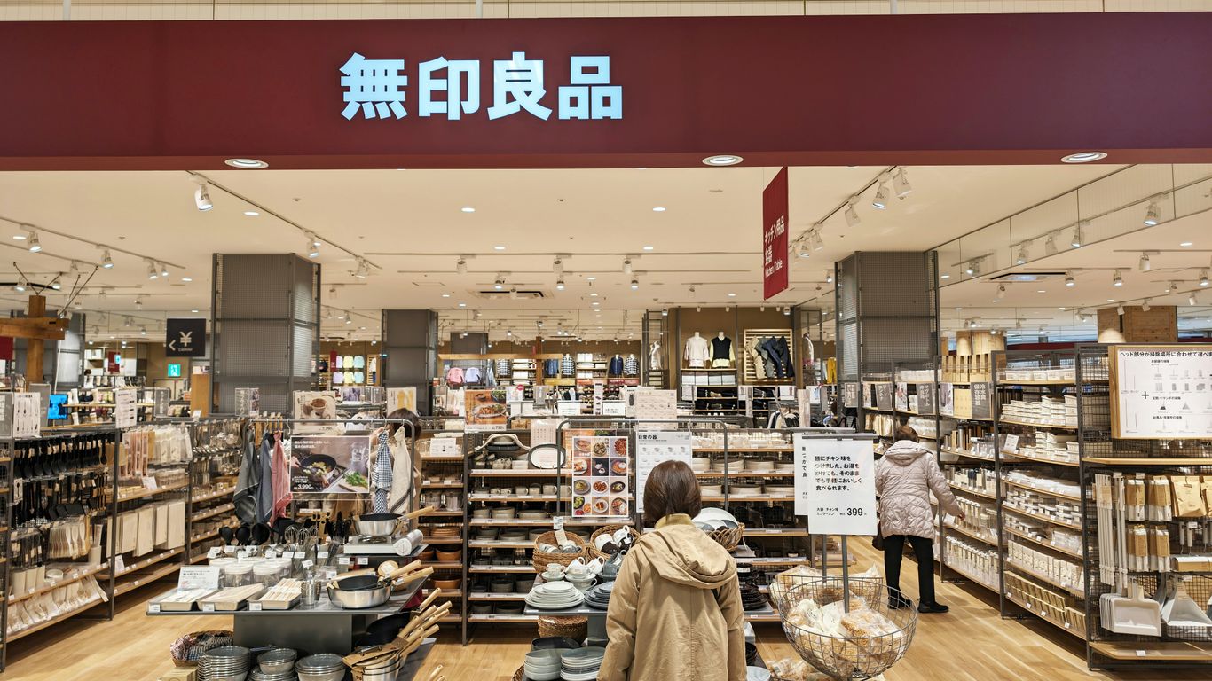 a woman standing in front of a store filled with items