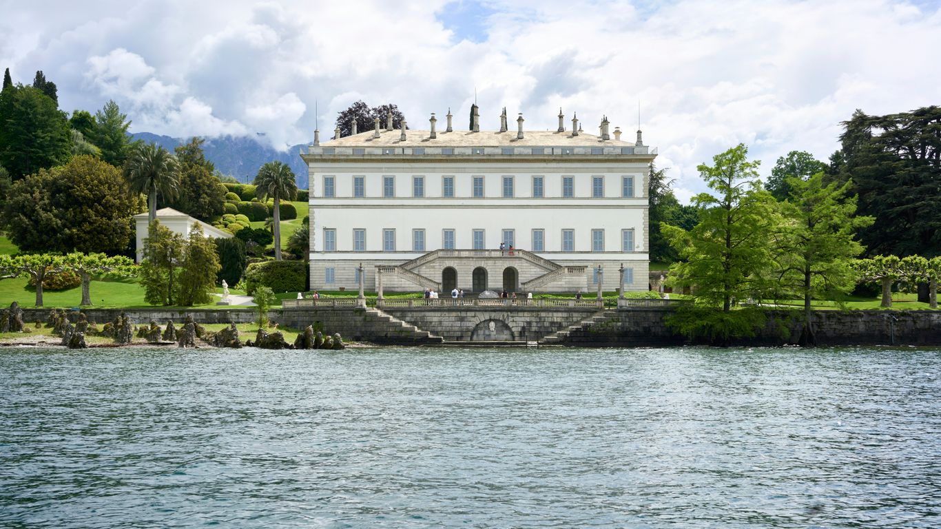 a large white building sitting on top of a lush green hillside