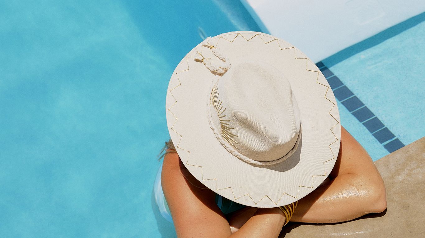 Two people relaxing by a pool with a drink.