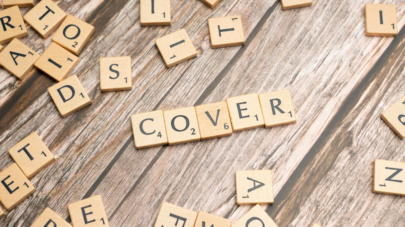 scrabble tiles spelling the word cover on a wooden surface