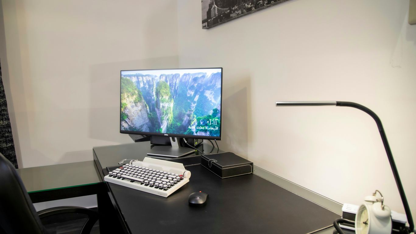 black flat screen computer monitor on black wooden desk