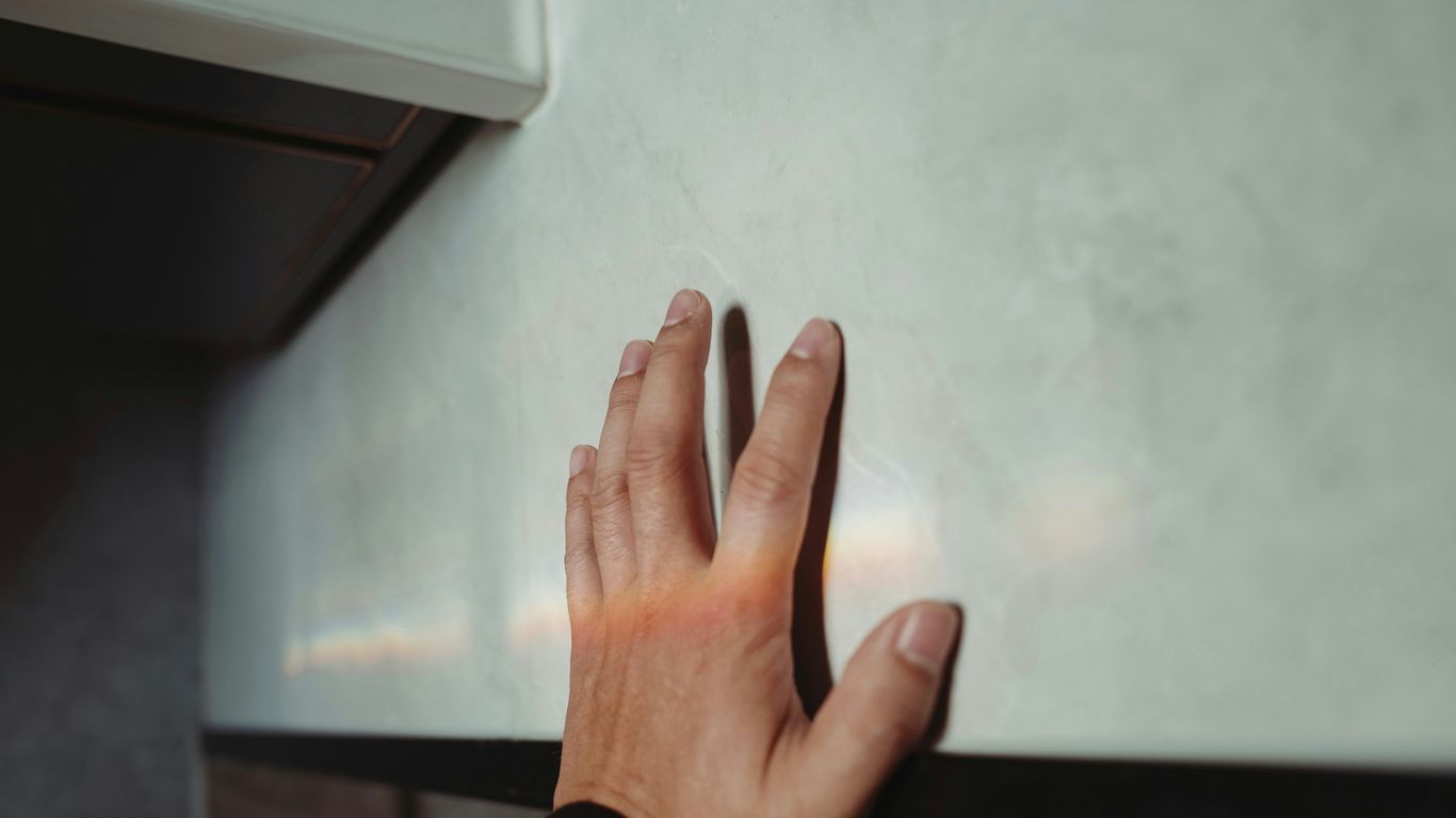 A person's hand reaching for something on a counter