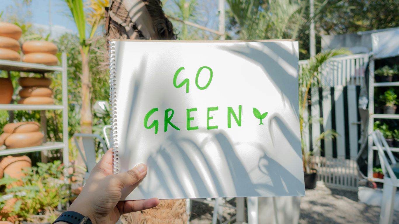 a person holding up a sign that says go green
