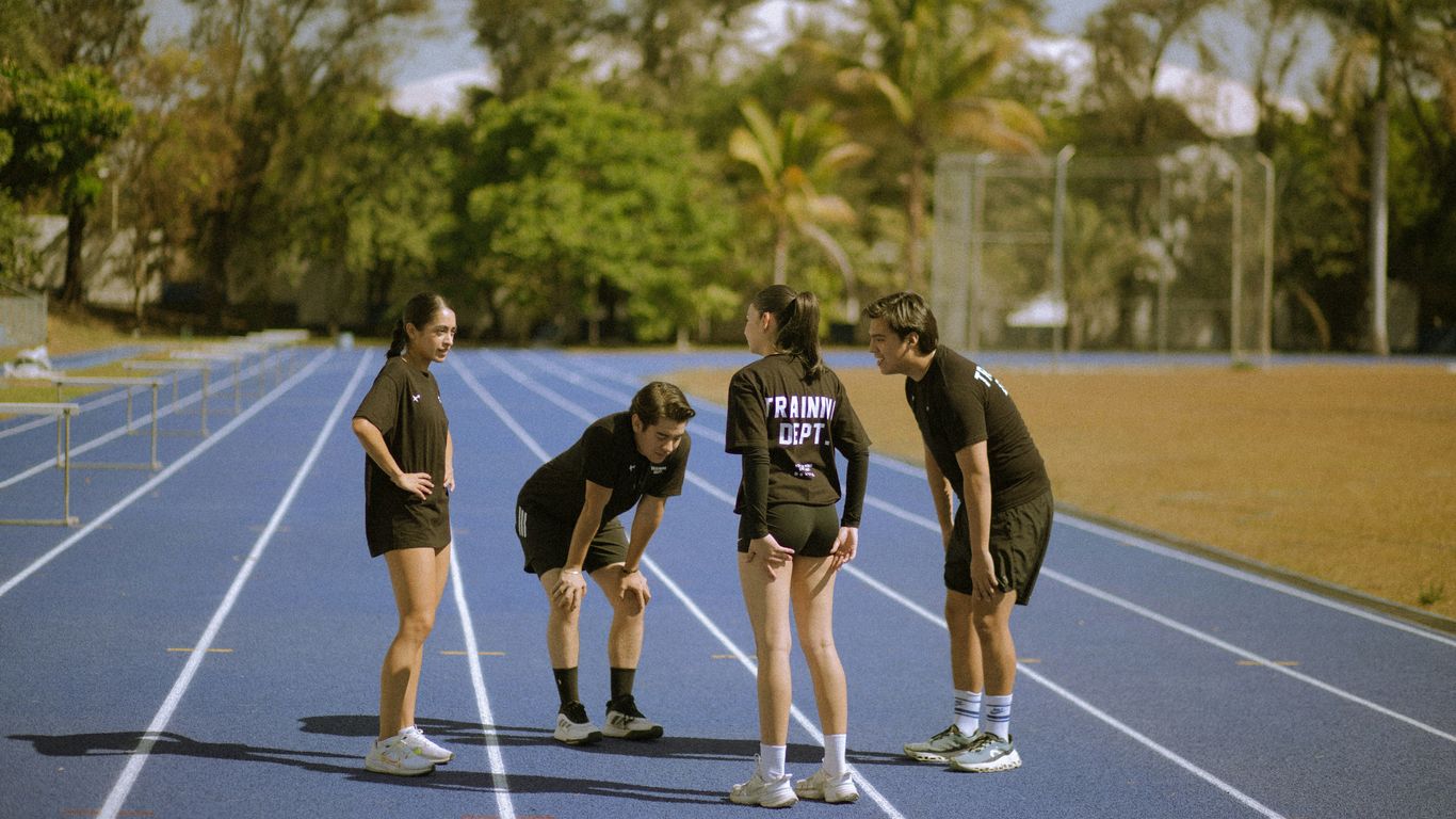 Four athletes in black on a blue running track
