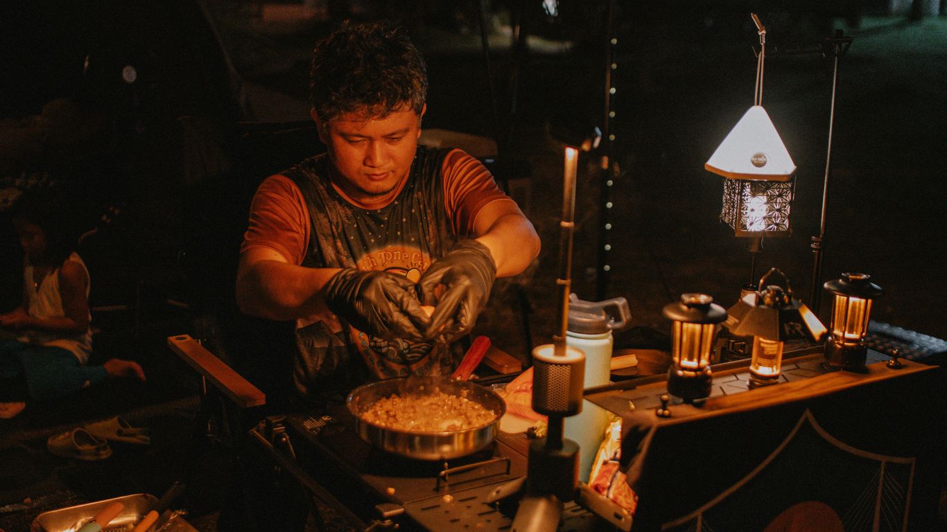 A person prepares food at a campsite.