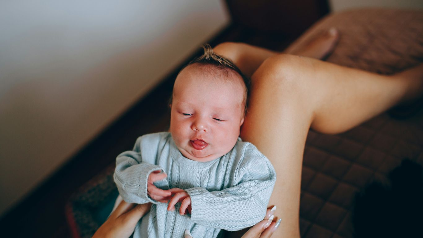woman carrying baby in blue and white blanket