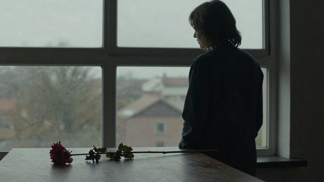 Pessoa em luto olhando pela janela.