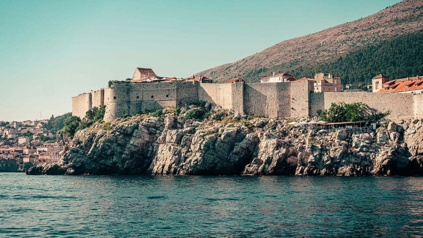 brown concrete building on rock formation near body of water during daytime
