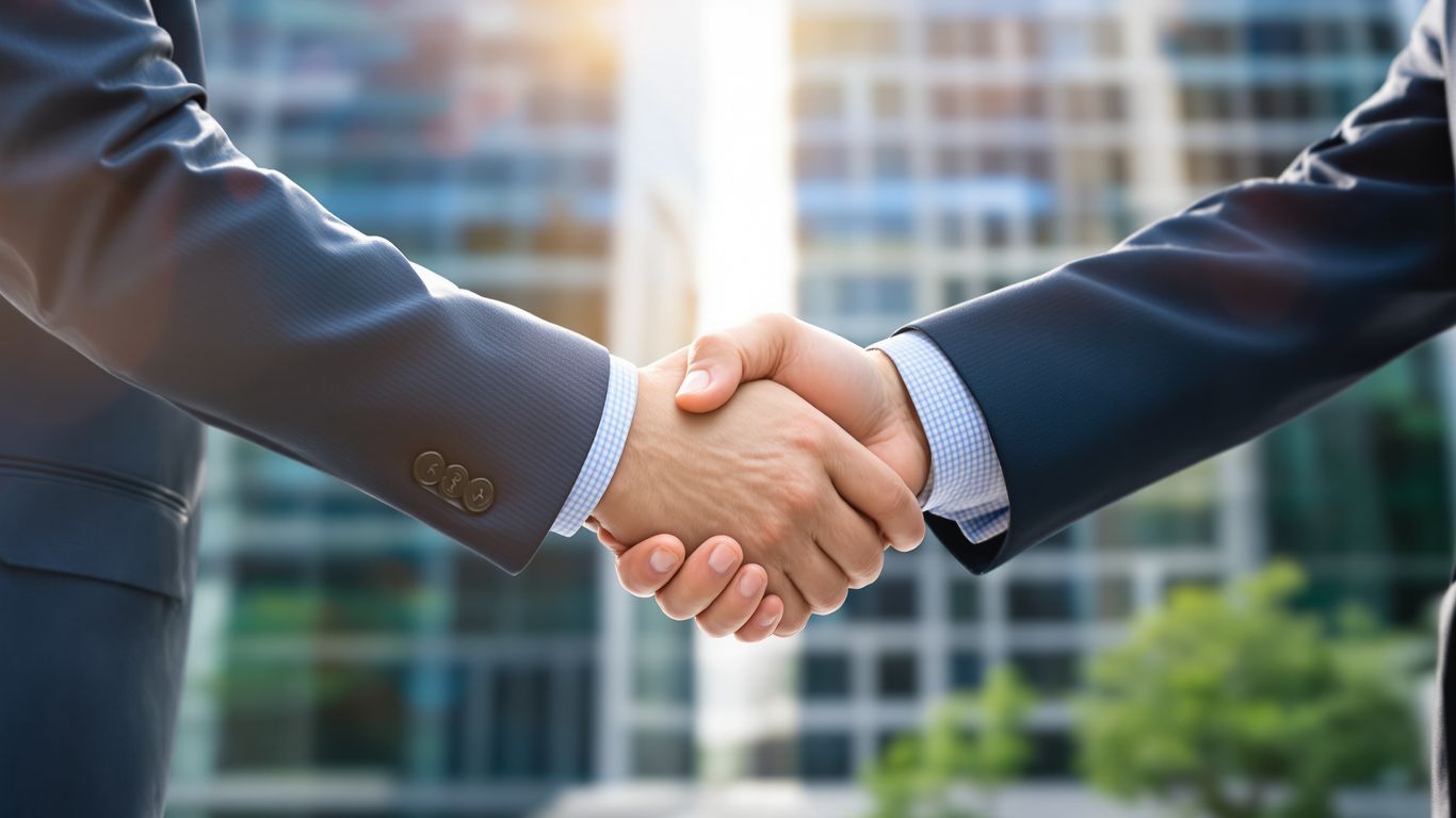 Business handshake with sunlight and office buildings.