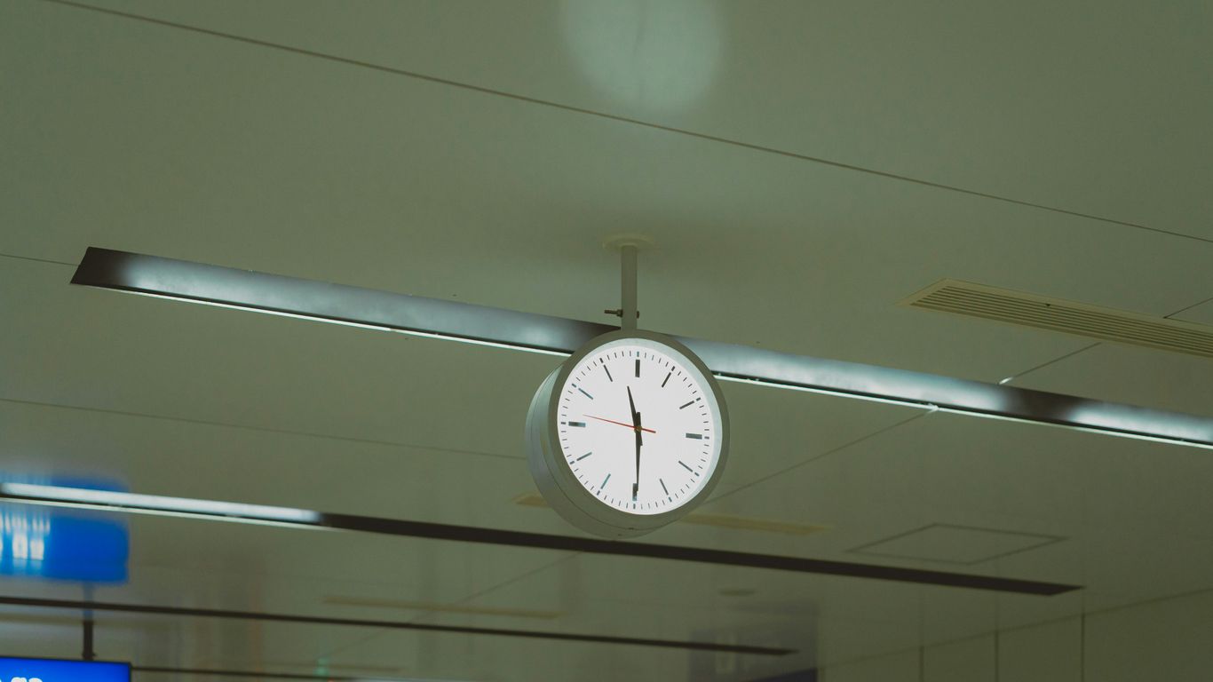 A clock hanging from the ceiling of an airport