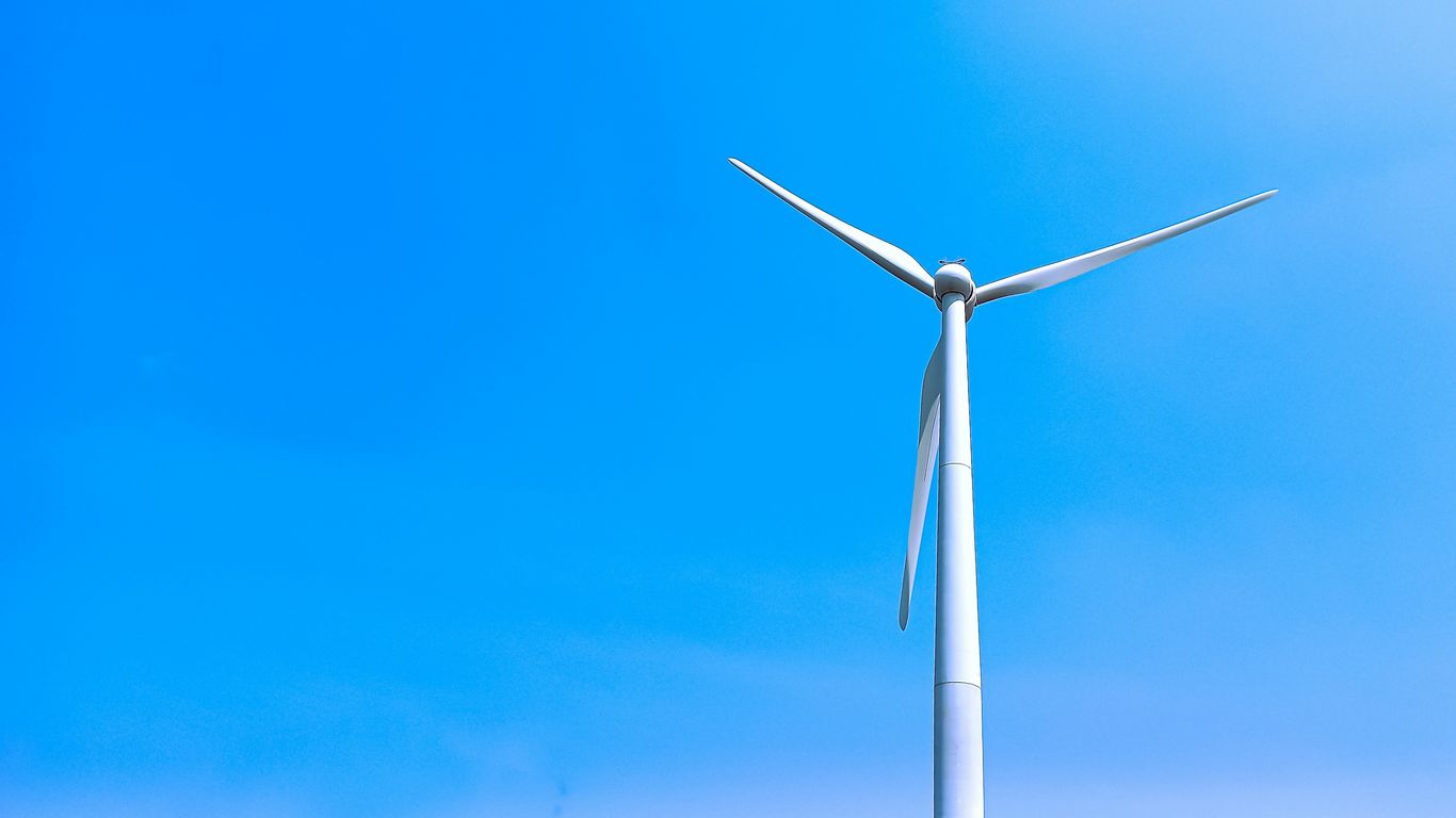 A wind turbine is shown against a blue sky