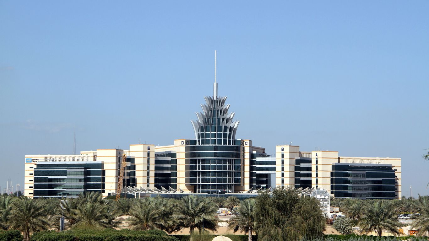 white and blue concrete building near green trees under blue sky during daytime