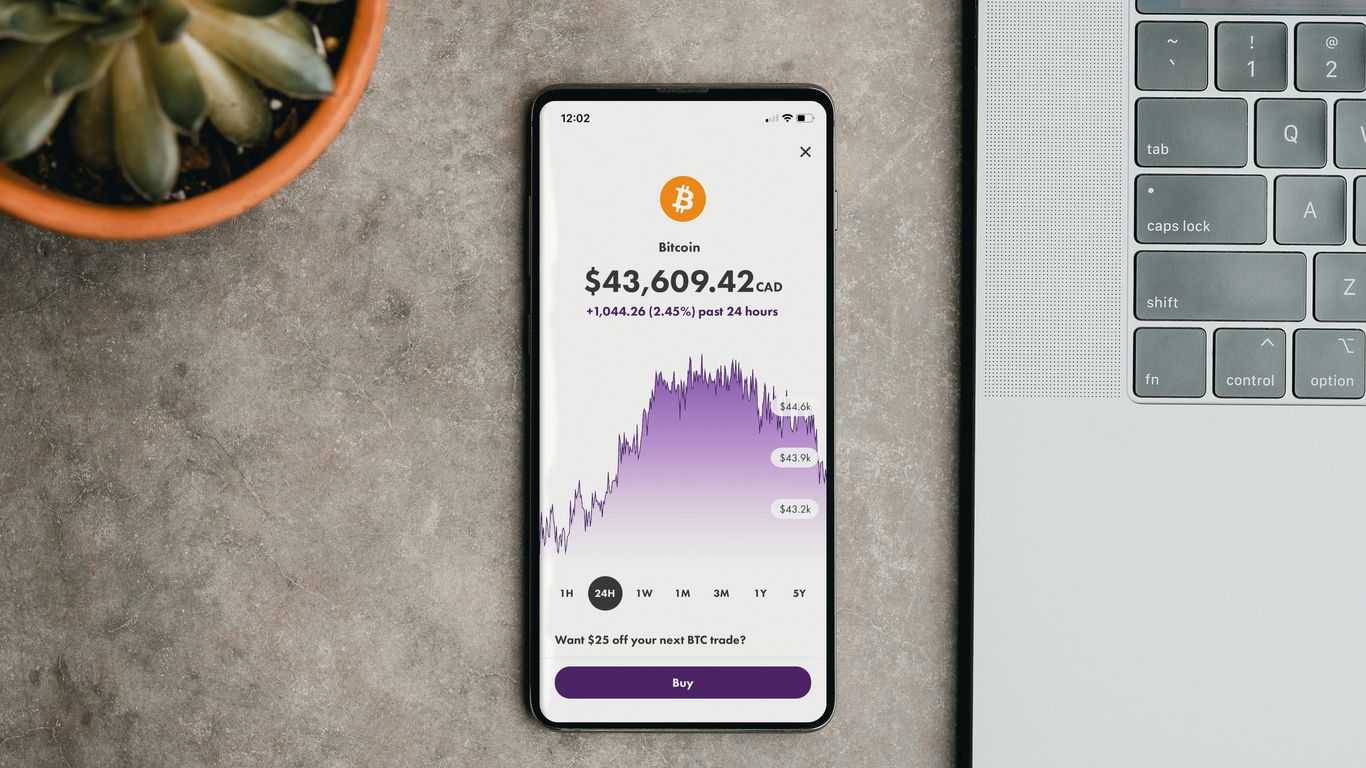 A smartphone displaying Bitcoin price next to a laptop.