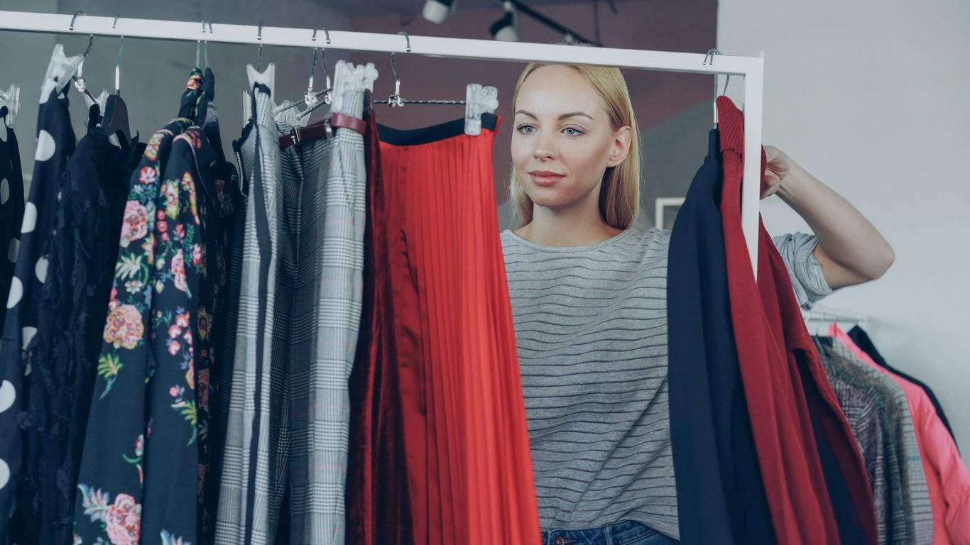 Woman chooses clothes from a clothing rack.