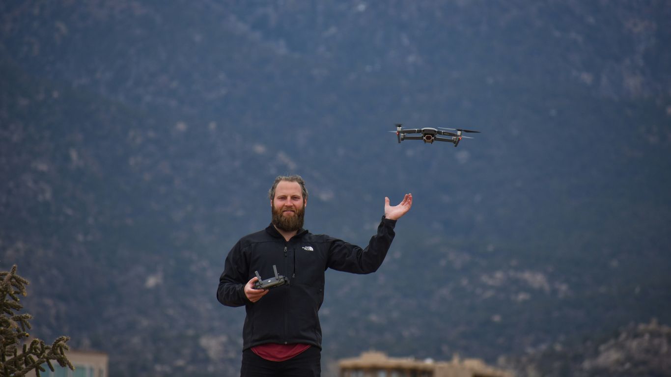 man in black jacket holding black and gray drone