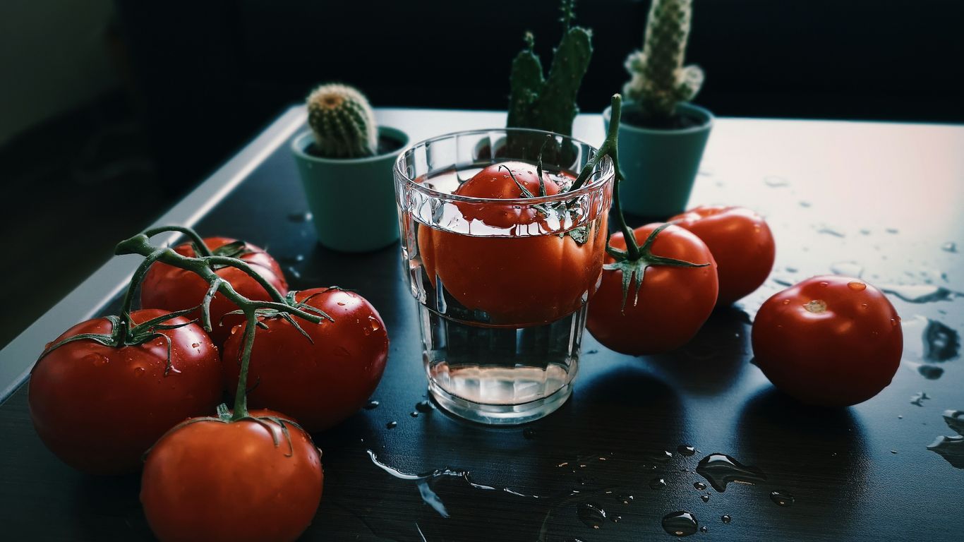 red tomato fruit beside clear drinking glass