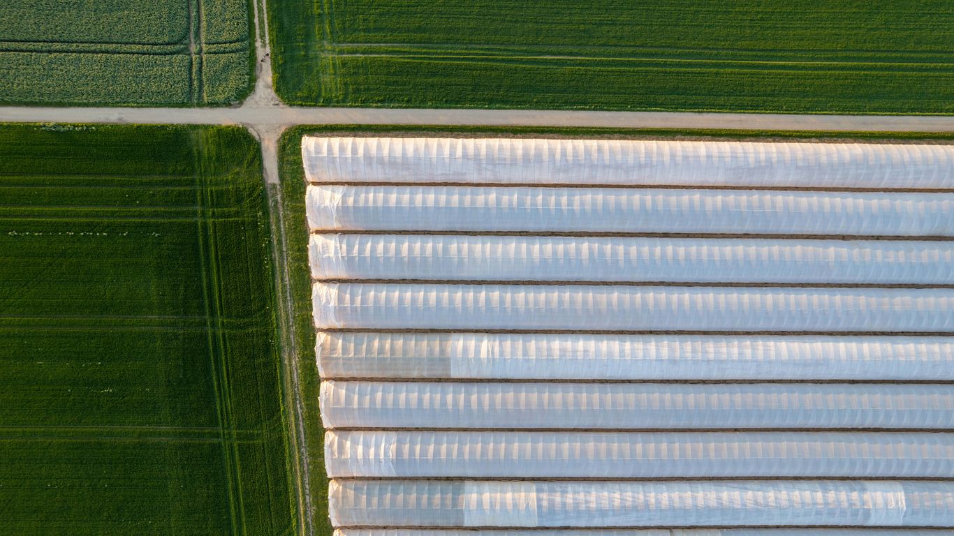 an aerial view of a green field and a white building