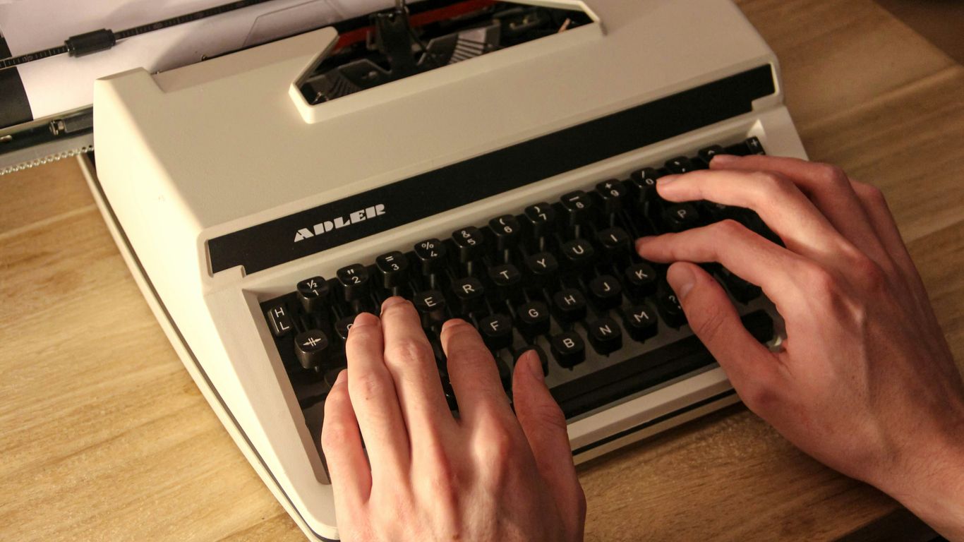 person holding gray and black typewriter