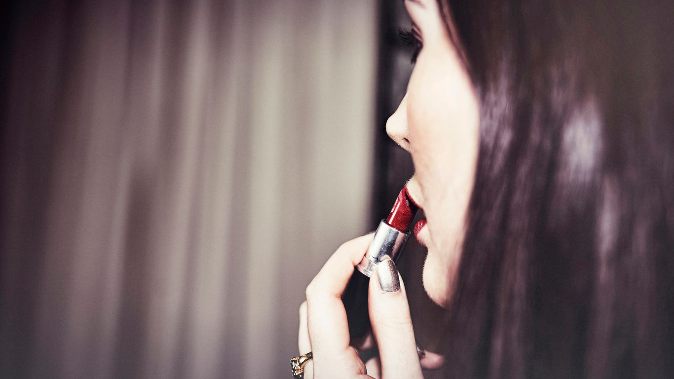 woman putting red lipstick in her lips