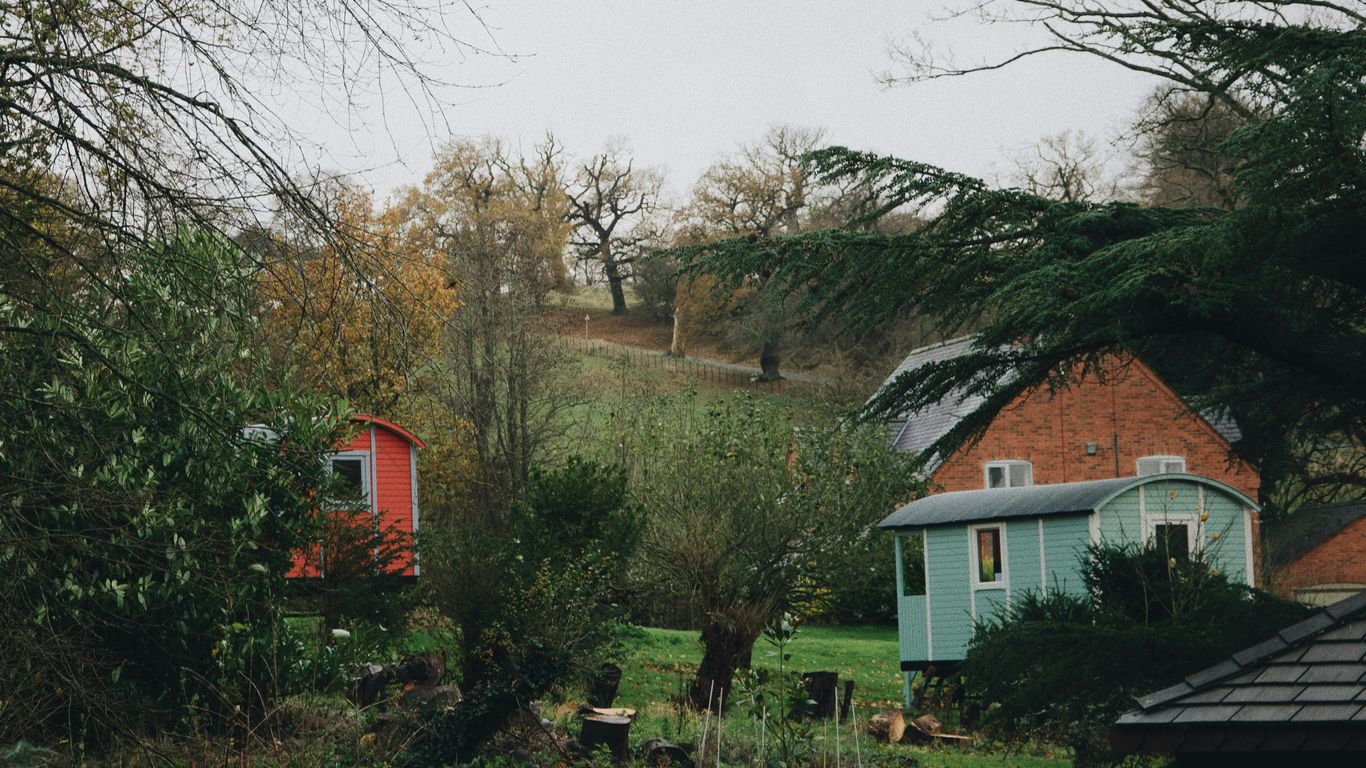 a couple of houses sitting on top of a lush green hillside