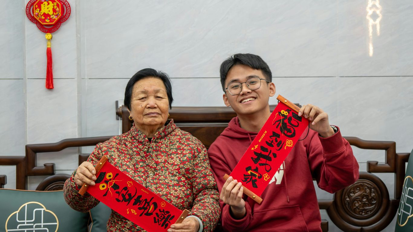 a man and woman sitting on a couch holding up signs