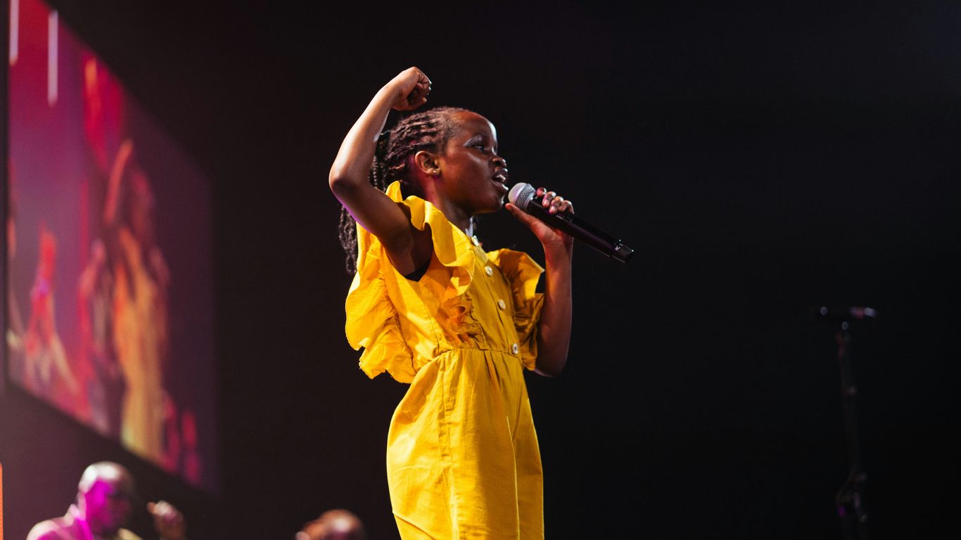 A girl in yellow sings on stage.