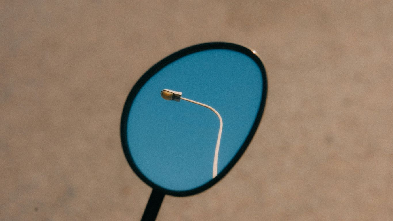 a close up of a mirror with a street light in the reflection