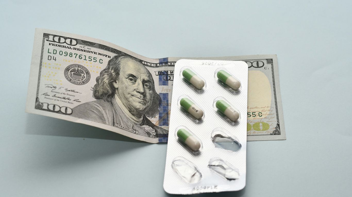 a pack of pills sitting on top of a hundred dollar bill