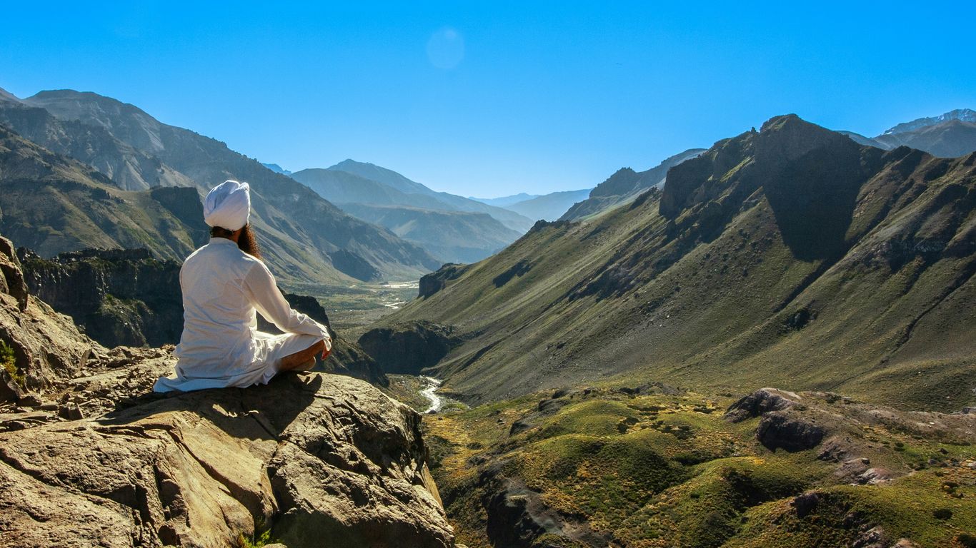 a person sitting on a rock looking out over a valley